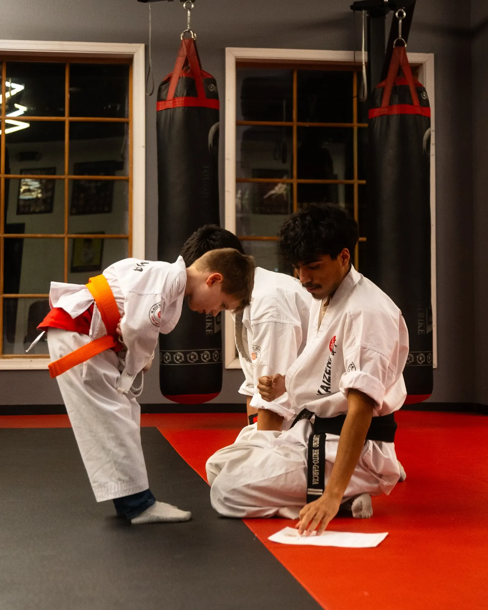 Kaizen MMA instructor teaching a young student with an orange belt